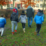 uczniowie jak ekologiczny patrol idą za panem przyrodnikiem, żeby oglądać budki w ogrodzie