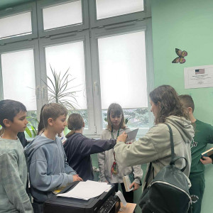 uczniowie stoją przy biurku