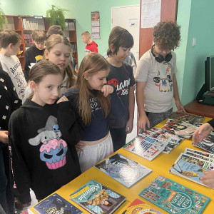 Uczniowie stoją przy stolikach