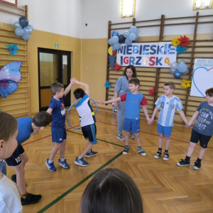 Dzieci trzymając się za ręce próbują przekazać hula-hop kolejnej osobie bez puszczenia rąk