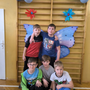 Grupa dzieci na tle skrzydeł motyla uśmiecha się do zdjęcia