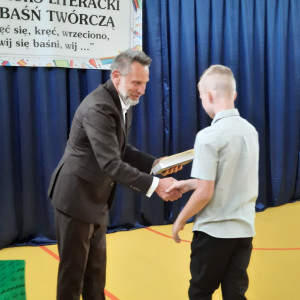 Pan dyrektor wręcza nagrodę uczniowi.