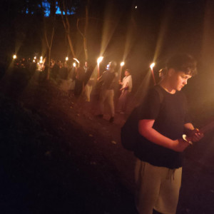 Uczniowie nocą spacerują z pochodniami.