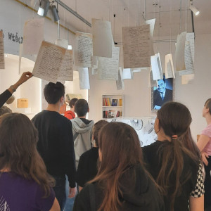 Uczniowie oglądają kartki z rękopisami powieści zawieszone u sufitu...