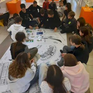 Uczniowie siedzą na podłodze i układają historyjkę obrazkową.