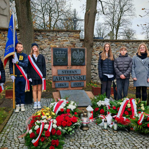 Uczniowie reprezentujący szkołę na obchodach rocznicy śmierci patrona stoją przy jego grobie.