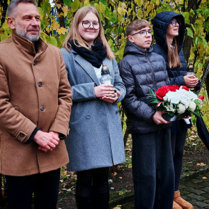 Dyrektor szkoły wraz z delegacją uczniów oczekują na złożenie kwiatów na grobie patrona.