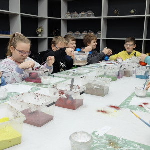 Dzieci dekorują bombki różnymi kolorami farb.