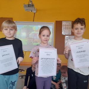 Przedszkolaki prezentują plansze ze zwrotami grzecznościowymi.