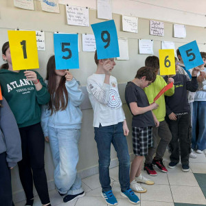 uczniowie stoją na korytarzu trzymając kolorowe kartki