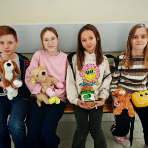 Czworo uczniów z klasy 6 siedzi na ławce i trzyma przed sobą małe maskotki.